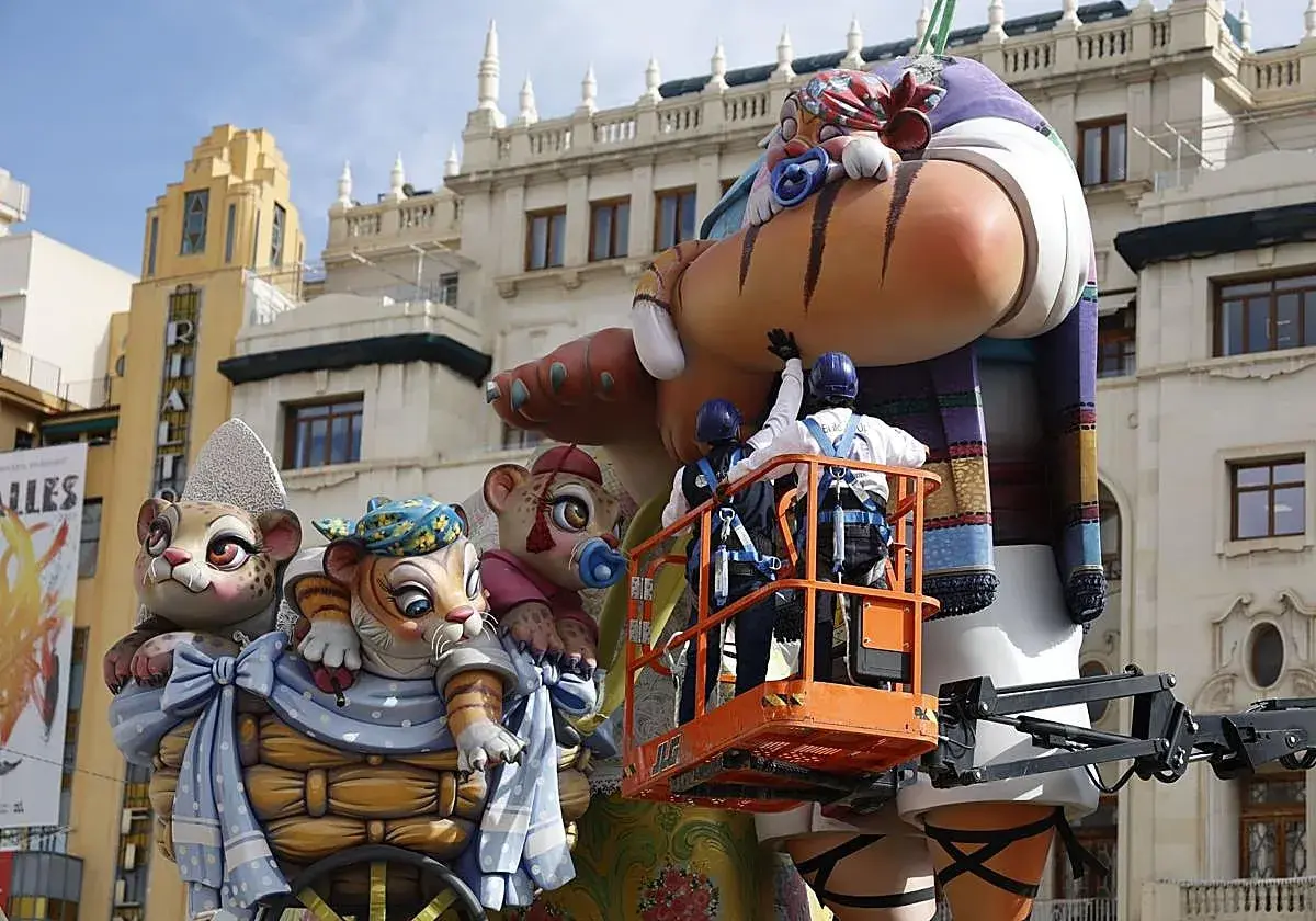 Dos operarios en una grúa trabajan en una falla gigante con figuras de animales. Se acerca el momento cuando es la planta.