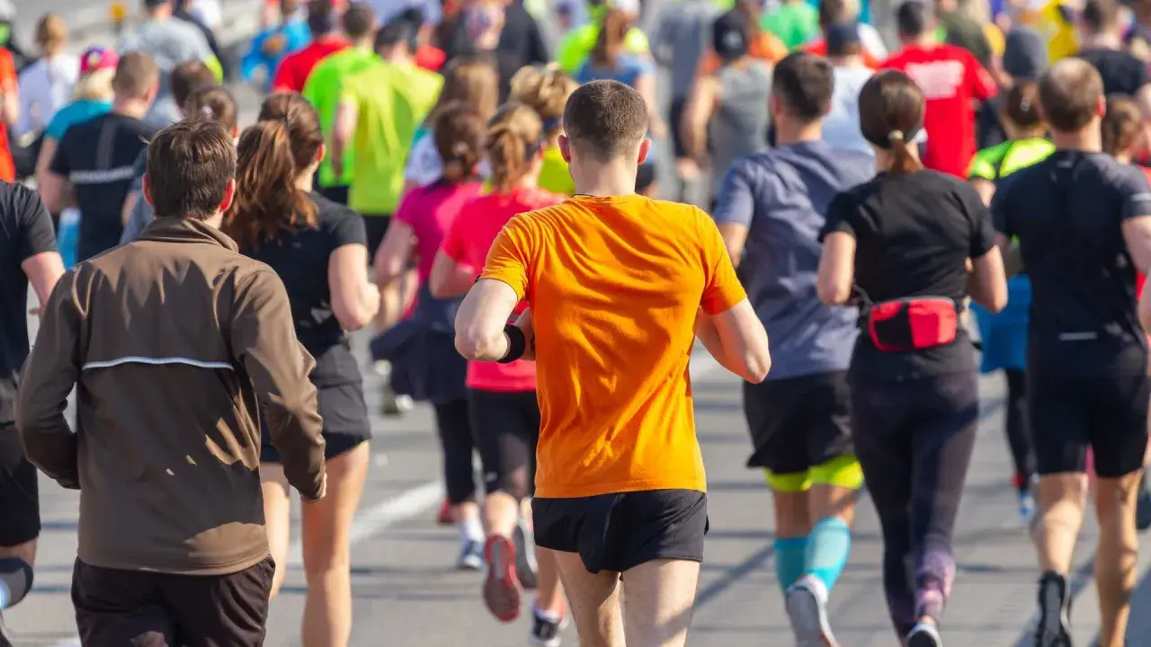 Corredores en la carrera 30k Sagunto, con un hombre de naranja en primer plano.
