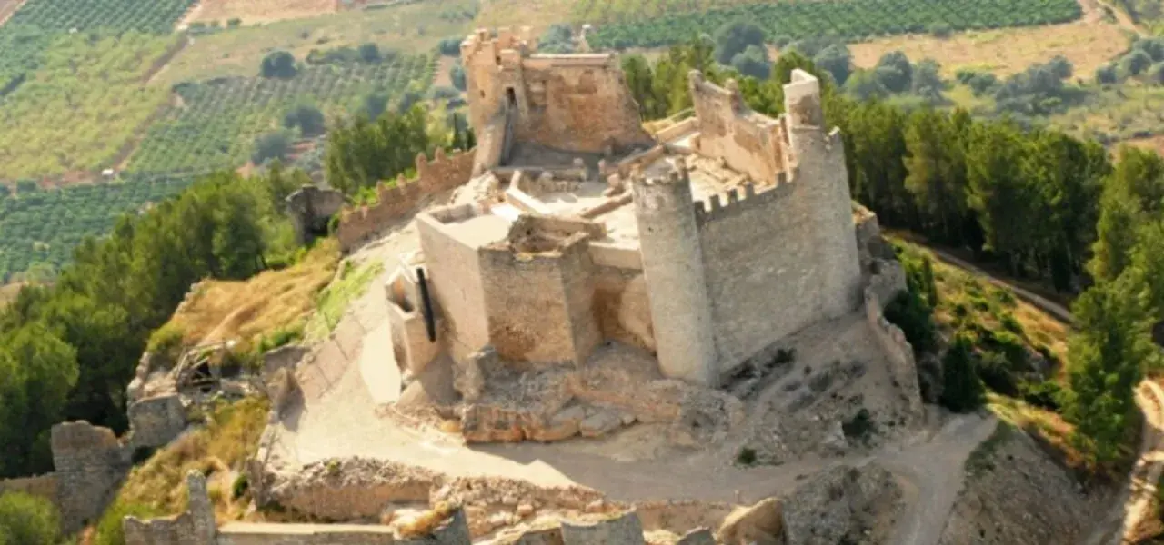 El imponente castillo de Xivert se alza sobre una colina, rodeado de vegetación y campos cultivados. Sus ruinas cuentan historias de batallas y tiempos pasados.