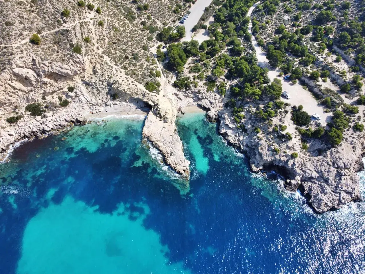 Vista aérea del racó del conill, una cala escondida con aguas cristalinas y rocas escarpadas.
