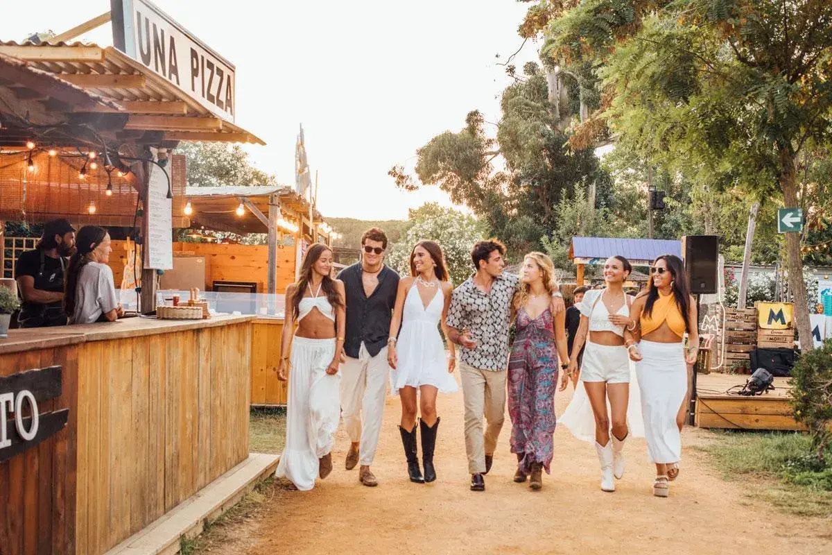 Un grupo de amigos pasea por un festival culinario en Valencia, disfrutando del ambiente veraniego y la buena compañía.