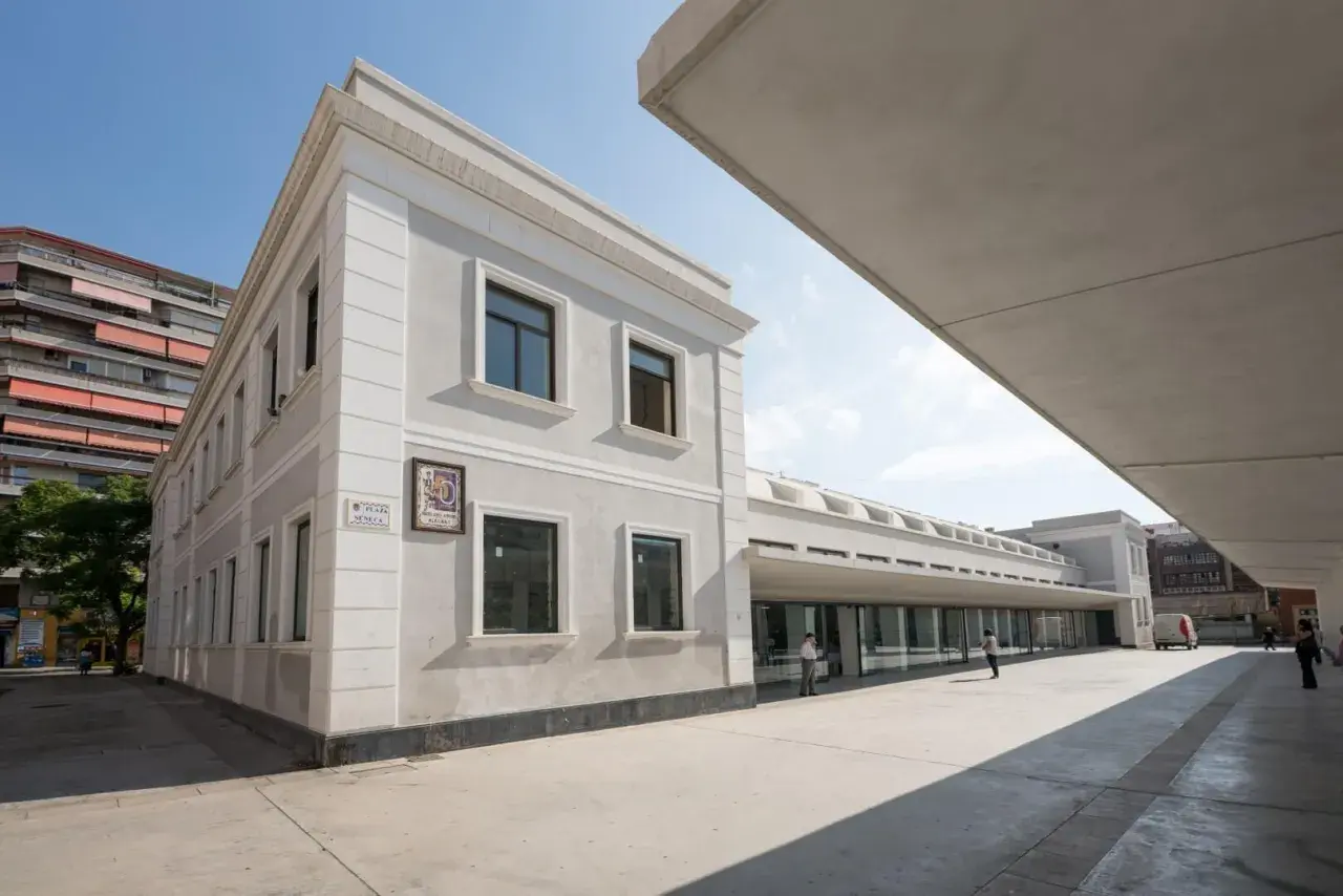 Edificio moderno y clásico en el **espacio Seneca Alicante**. Fachada gris, ventanas oscuras y un gran voladizo de hormigón.