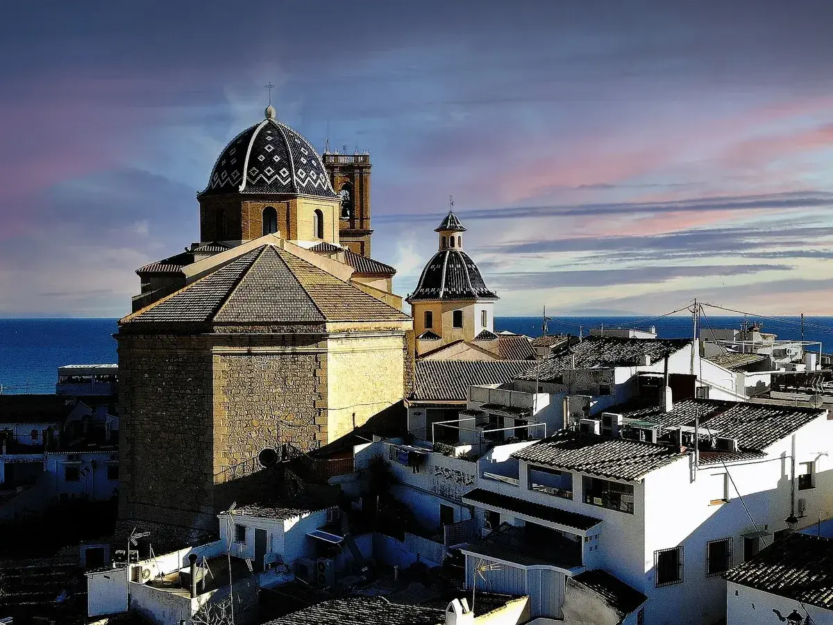 Altea vieille ville, con sus cúpulas y tejados blancos, se asoma al mar Mediterráneo bajo un cielo teñido de rosa y azul.