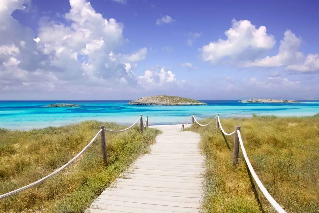 Camino de madera hacia las mejores playas del Levante. Aguas turquesas, arena blanca y un islote solitario.