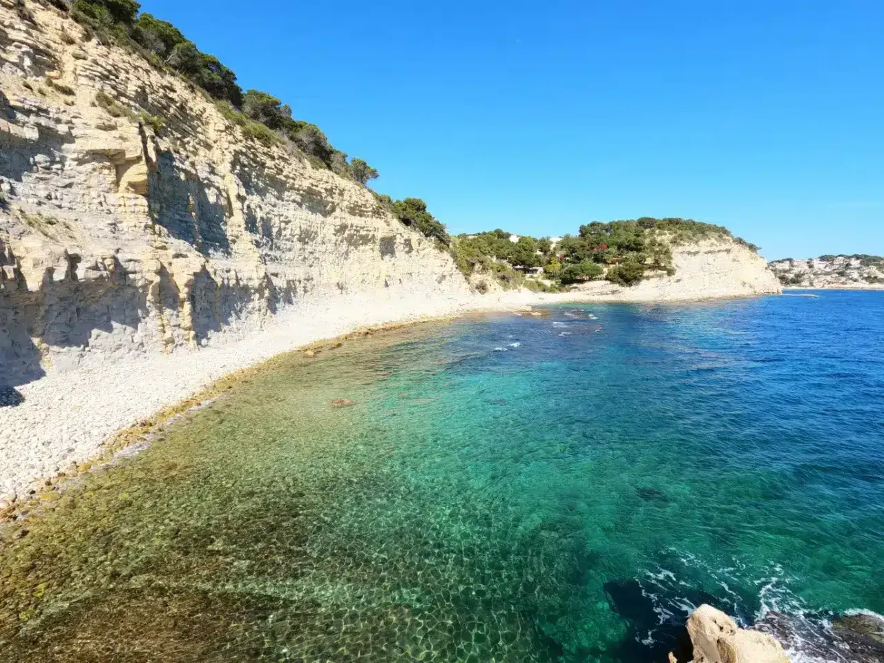 Aguas cristalinas y acantilados en la cala llobella, un paraíso mediterráneo.