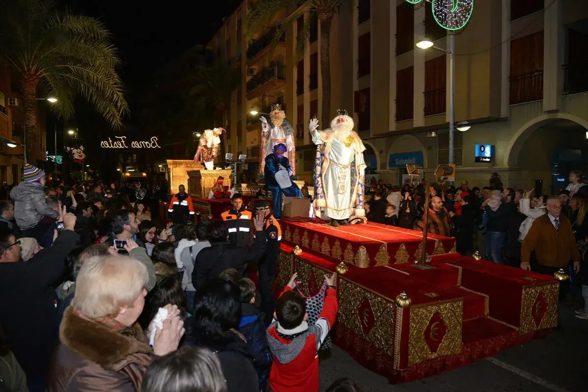 La cabalgata de Reyes en Valencia ilumina la noche con sus majestuosas carrozas y la multitud expectante. Melchor, Gaspar y Baltasar saludan a los niños.