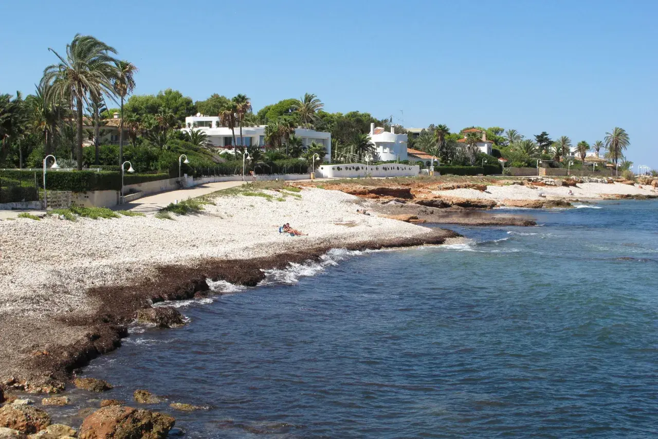 Un paseo junto a las mejores calas de Dénia, con casas blancas, palmeras y el mar azul.