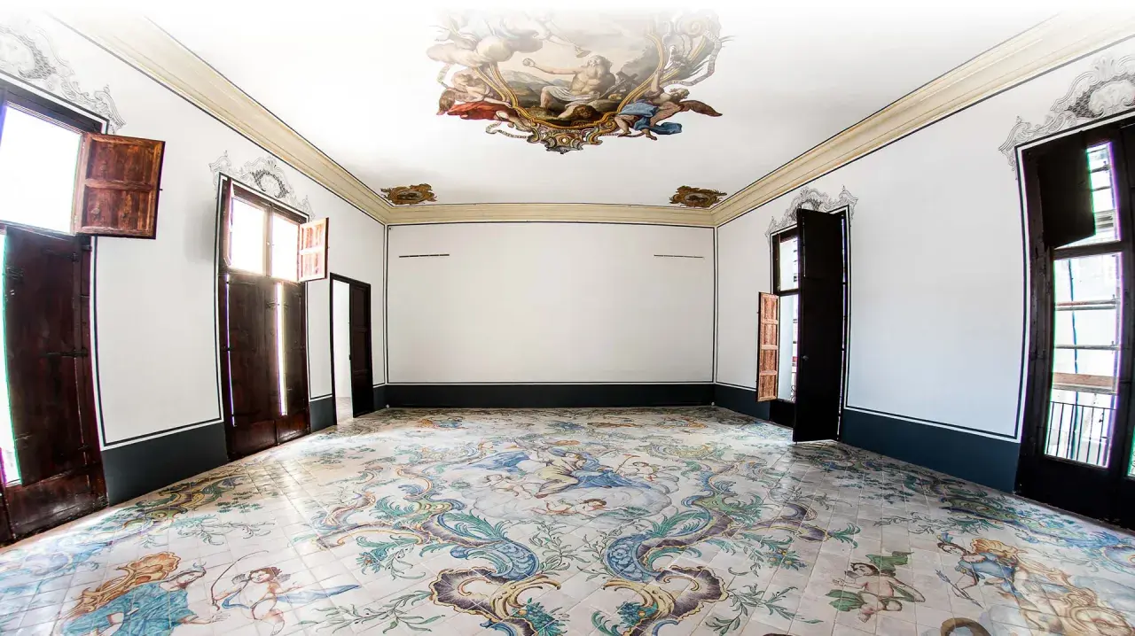 Interior de un museo de la seda con suelo de azulejos pintados y frescos en el techo.