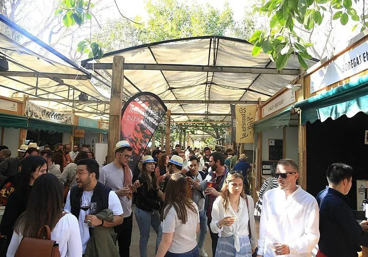 Gente disfrutando en la feria del vino Valencia, con puestos de degustación y ambiente festivo bajo toldos.