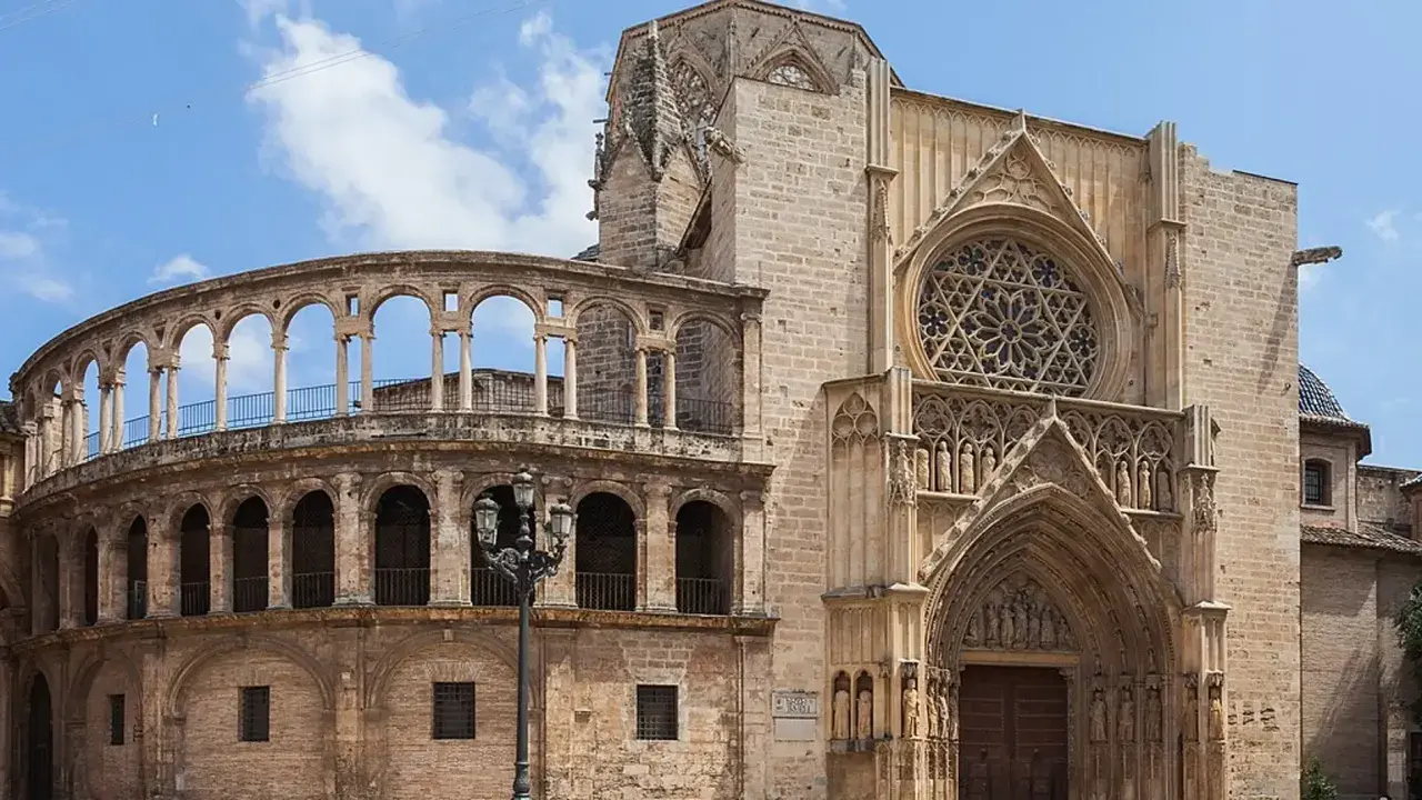La **catedral de Valencia** luce su fachada gótica con un rosetón y un pórtico detallado, junto a una estructura de arcos semicirculares.