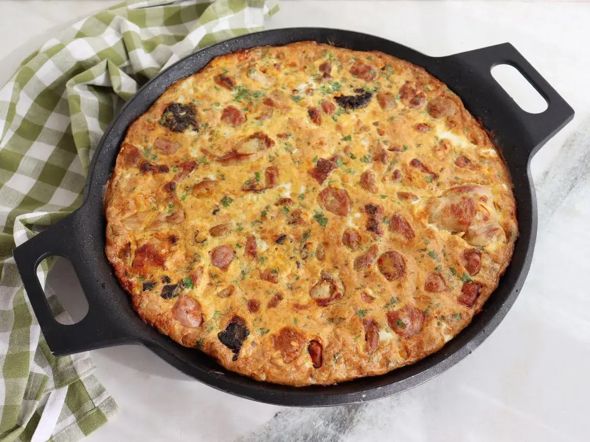 Arroz con costra de Elche recién hecho en sartén, con trozos de salchicha y perejil picado.