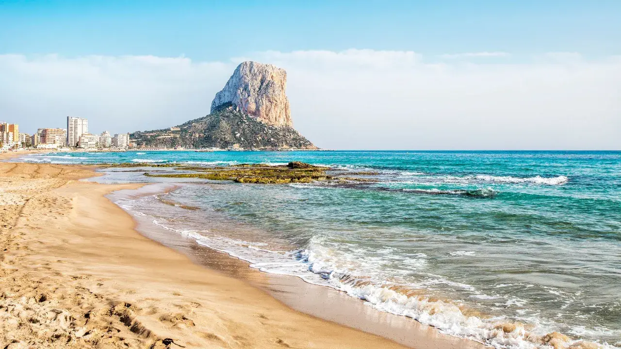 La playa de Calpe, con su arena dorada y el imponente Peñón de Ifach, invita a disfrutar del mar Mediterráneo.