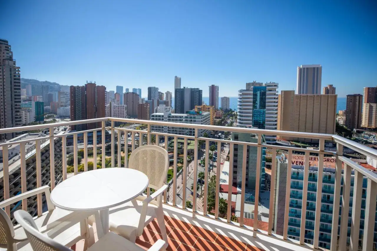Balcón con mesa y sillas, vistas a la ciudad y al mar desde un hotel pueblo Benidorm.