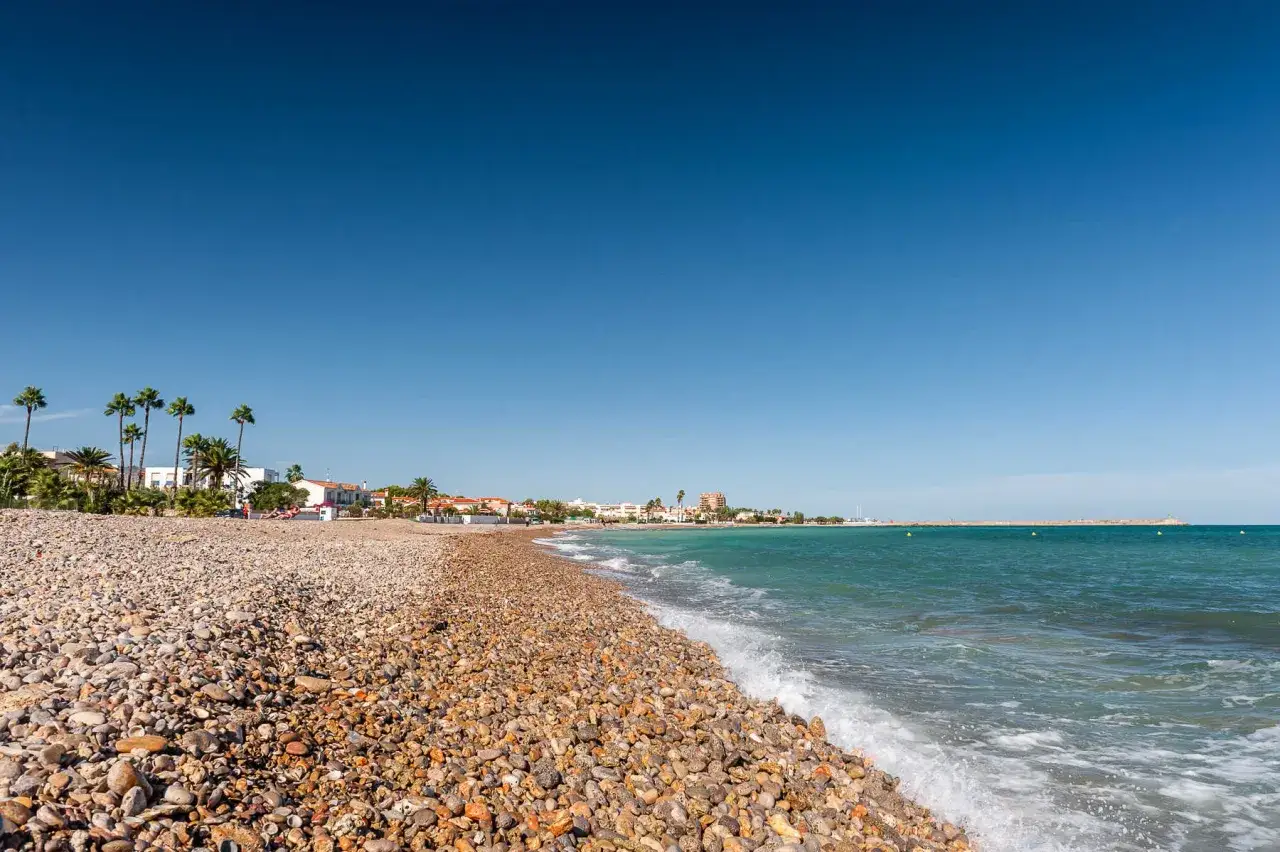 La playa Gurugú de Benicarló, con su guijarro y palmeras, invita a un día soleado junto al mar Mediterráneo.