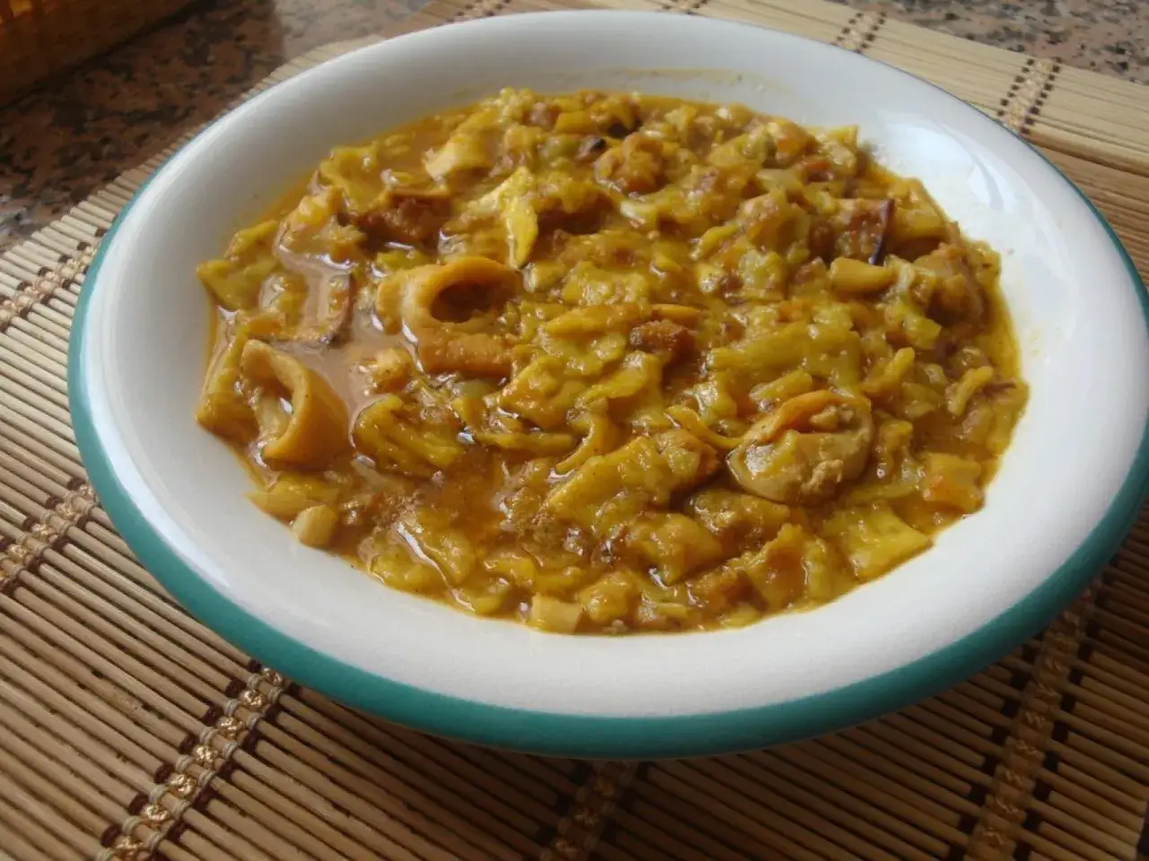 Un plato de gazpacho marinero alicantino, con trozos de pescado y calamar en una salsa dorada.