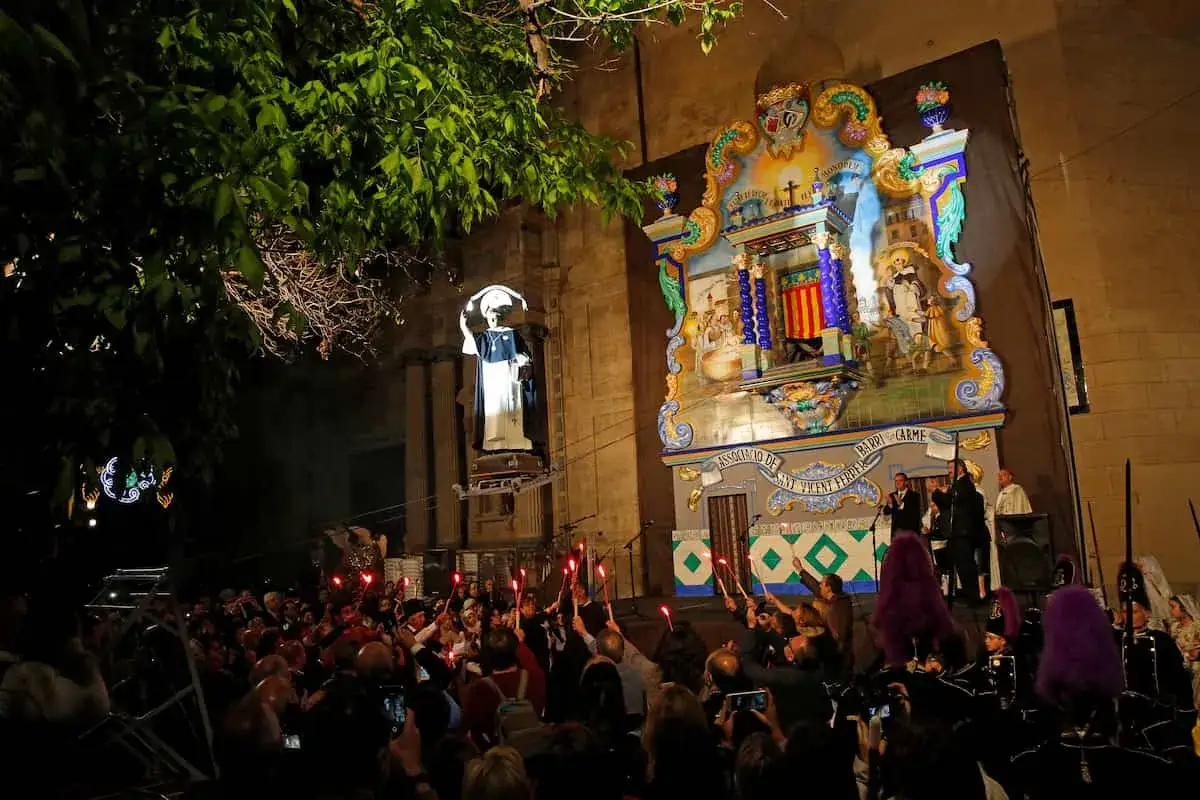 Procesi&oacute;n nocturna en Valencia cuando es San Vicente. Gente con antorchas ilumina la calle y una figura religiosa.