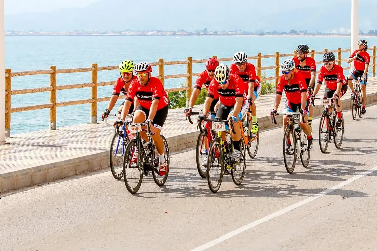 Ciclistas compiten en un gran fondo Valencia, pedaleando junto al mar azul.