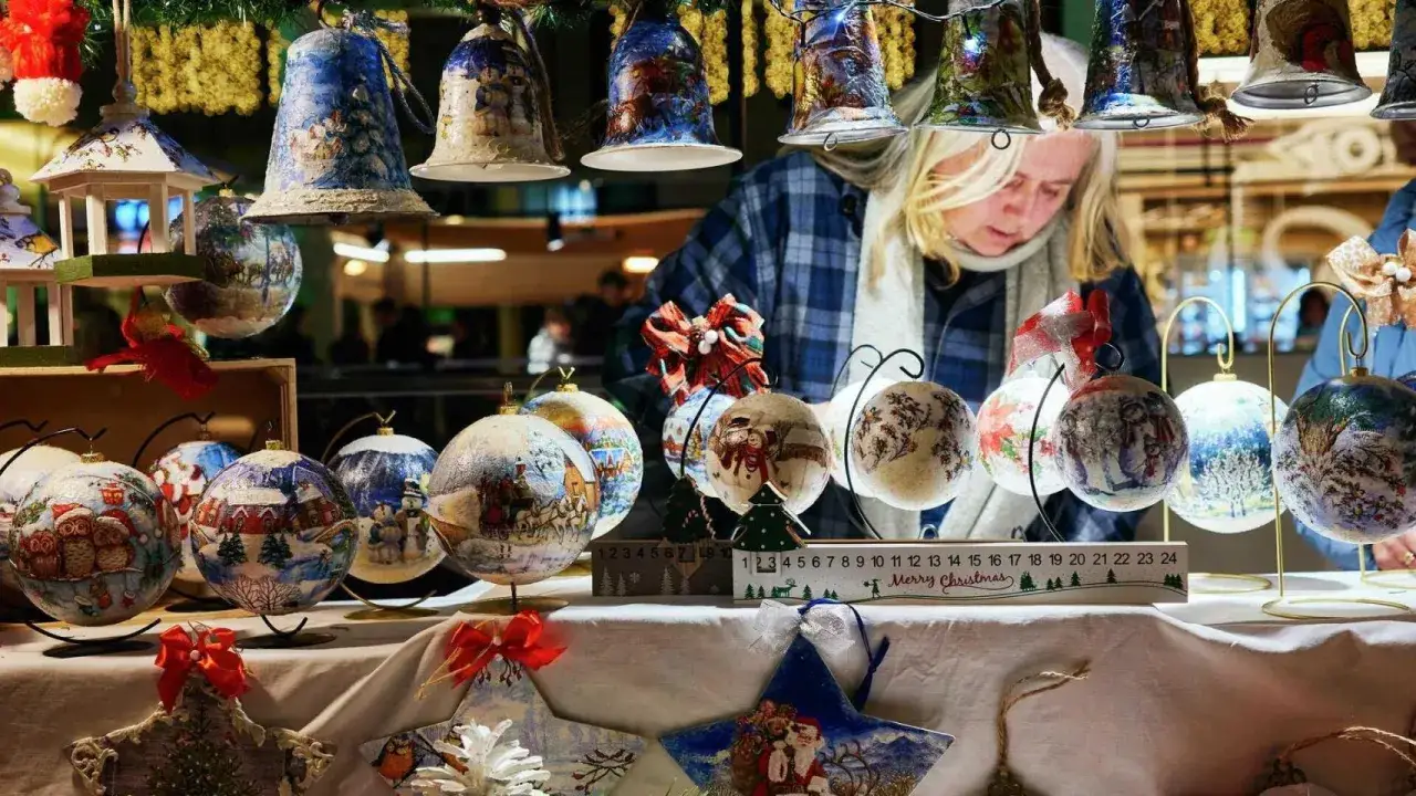 Adornos navideños pintados a mano en un puesto del Valencia Christmas market. Bolas con escenas invernales y campanas decoradas.