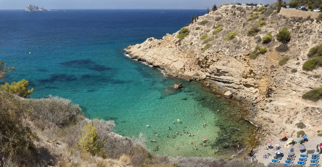 La cala Tío Ximo, con sus aguas cristalinas y rocas escarpadas, invita a disfrutar de un día soleado en la playa.