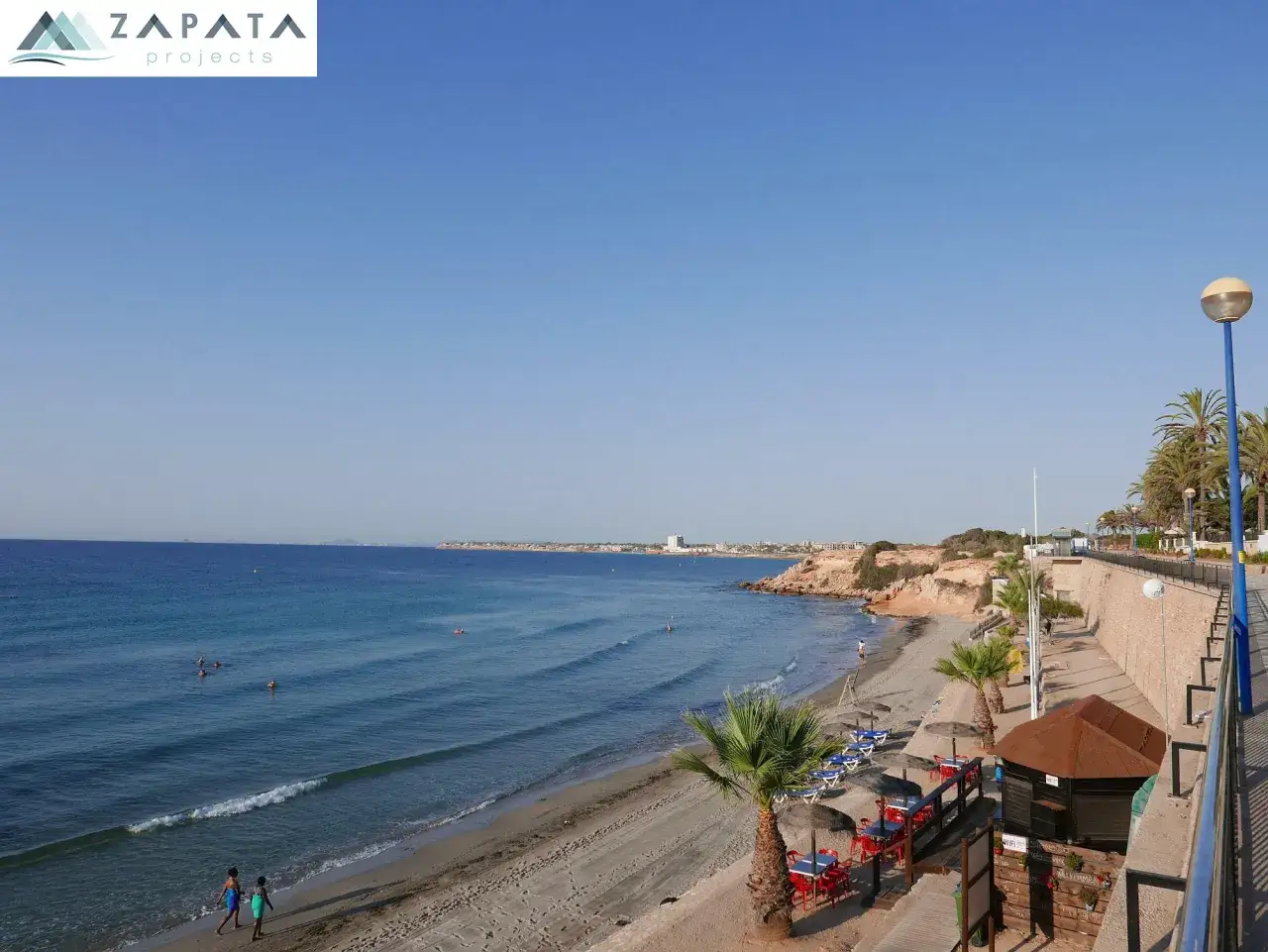 Vista de la playa Punta Prima con aguas turquesas, arena dorada y palmeras. Un día perfecto para disfrutar del sol y el mar.