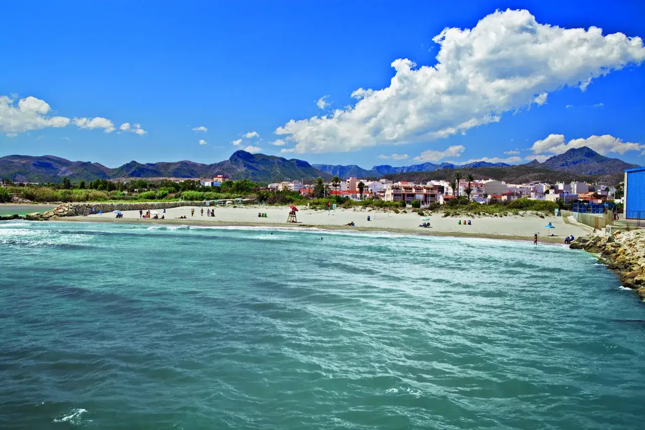 La playa Venecia de Gandía, con sus aguas turquesas y montañas al fondo, invita a disfrutar del sol y el mar.