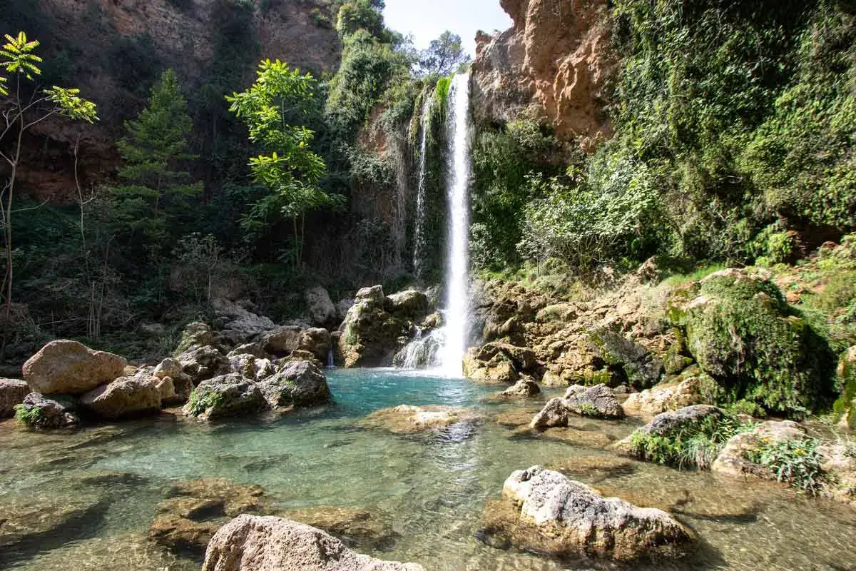 Cascada cae en el lago de Anna, rodeado de rocas y vegetación exuberante.