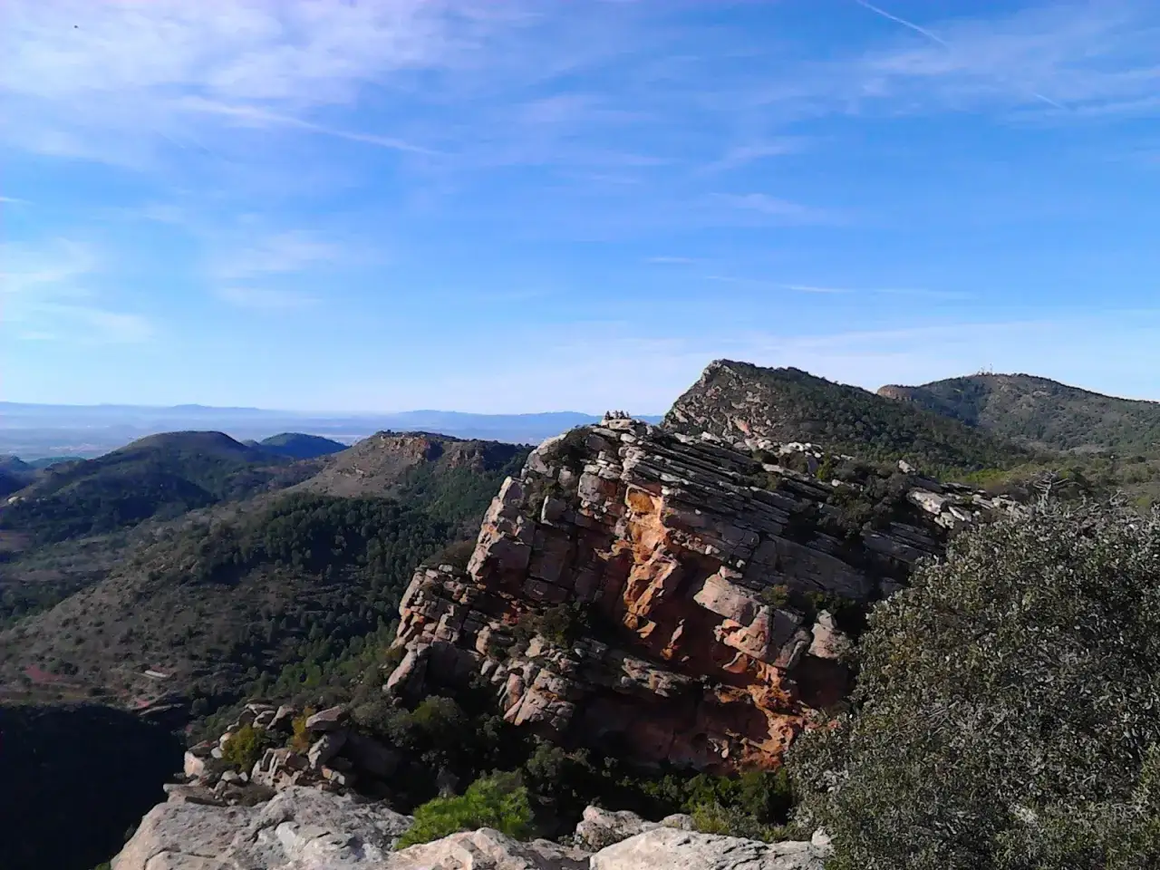 Majestuosas formaciones rocosas y verdes colinas se extienden bajo un cielo azul en la Sierra Calderona.