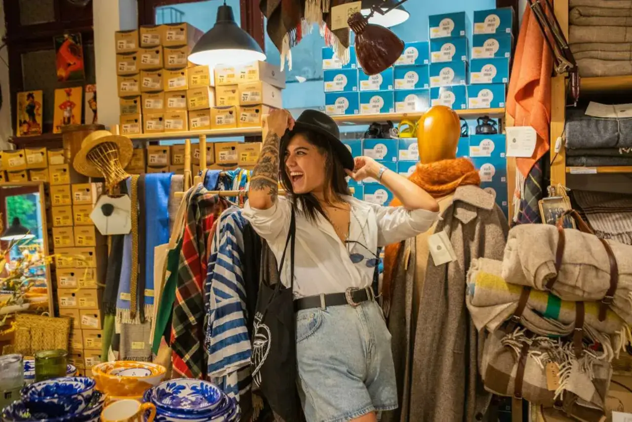 Joven feliz probándose un sombrero en una tienda de ropa de la winkelstraat Valencia.