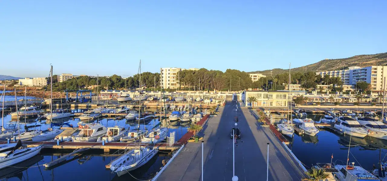 El puerto deportivo Las Fuentes, con sus barcos amarrados y el mar en calma, se extiende bajo un cielo azul claro.