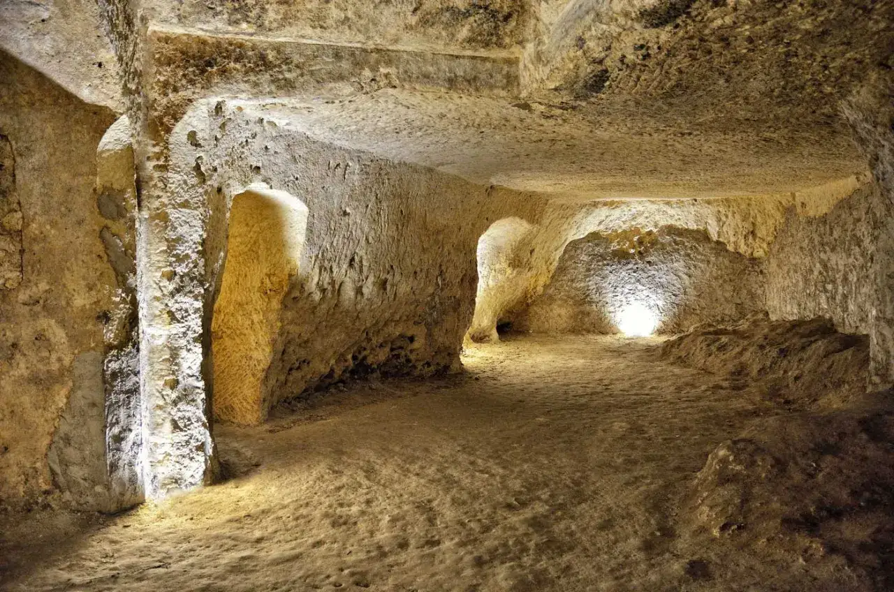 Interior de los covetes dels moros, cuevas excavadas en la roca con pasillos y nichos iluminados.