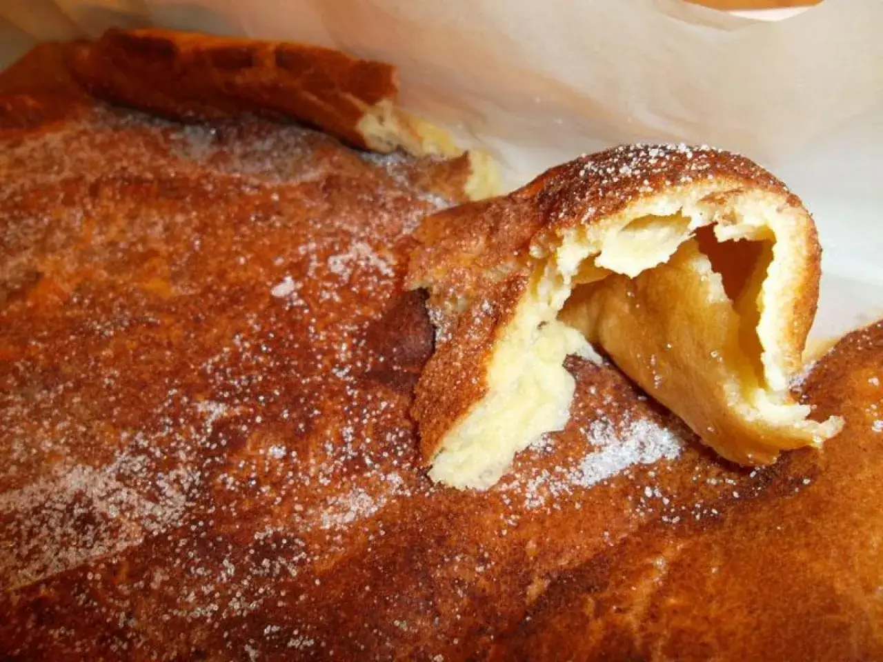 Un trozo de un postre típico alicante, con azúcar y canela espolvoreados, mostrando su interior esponjoso.