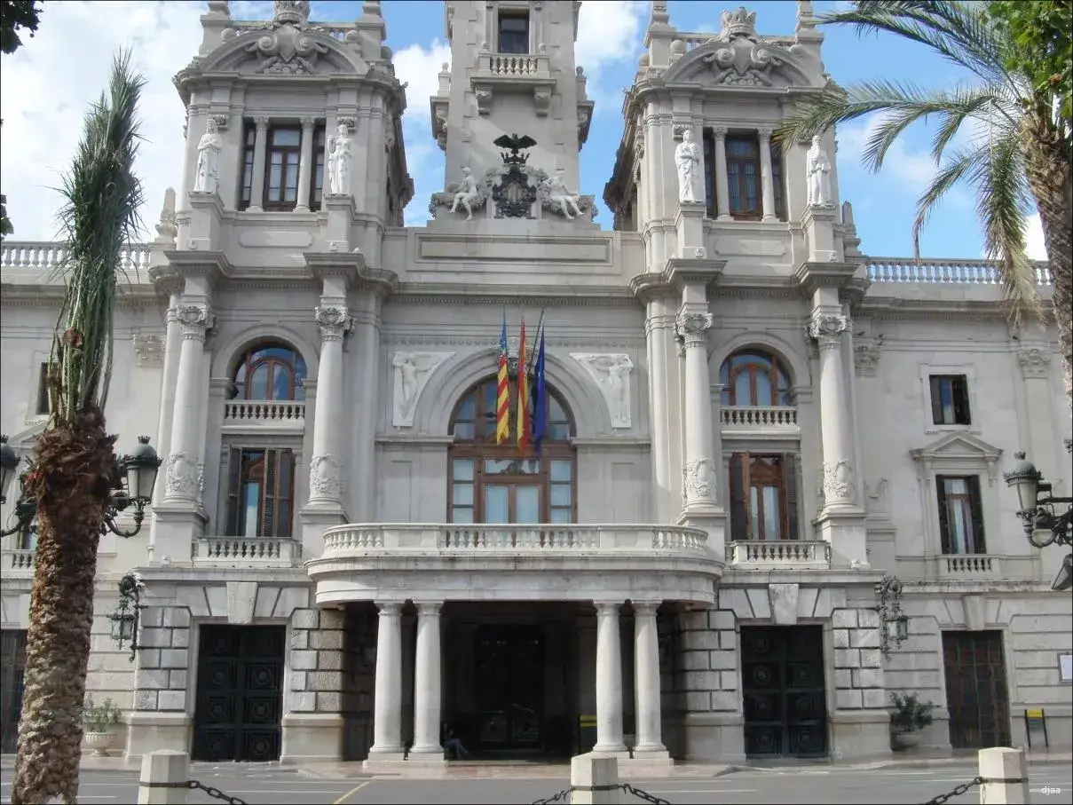 El Ayuntamiento de Valencia, con su imponente arquitectura y el escudo valencia visible, se alza majestuoso bajo un cielo azul.