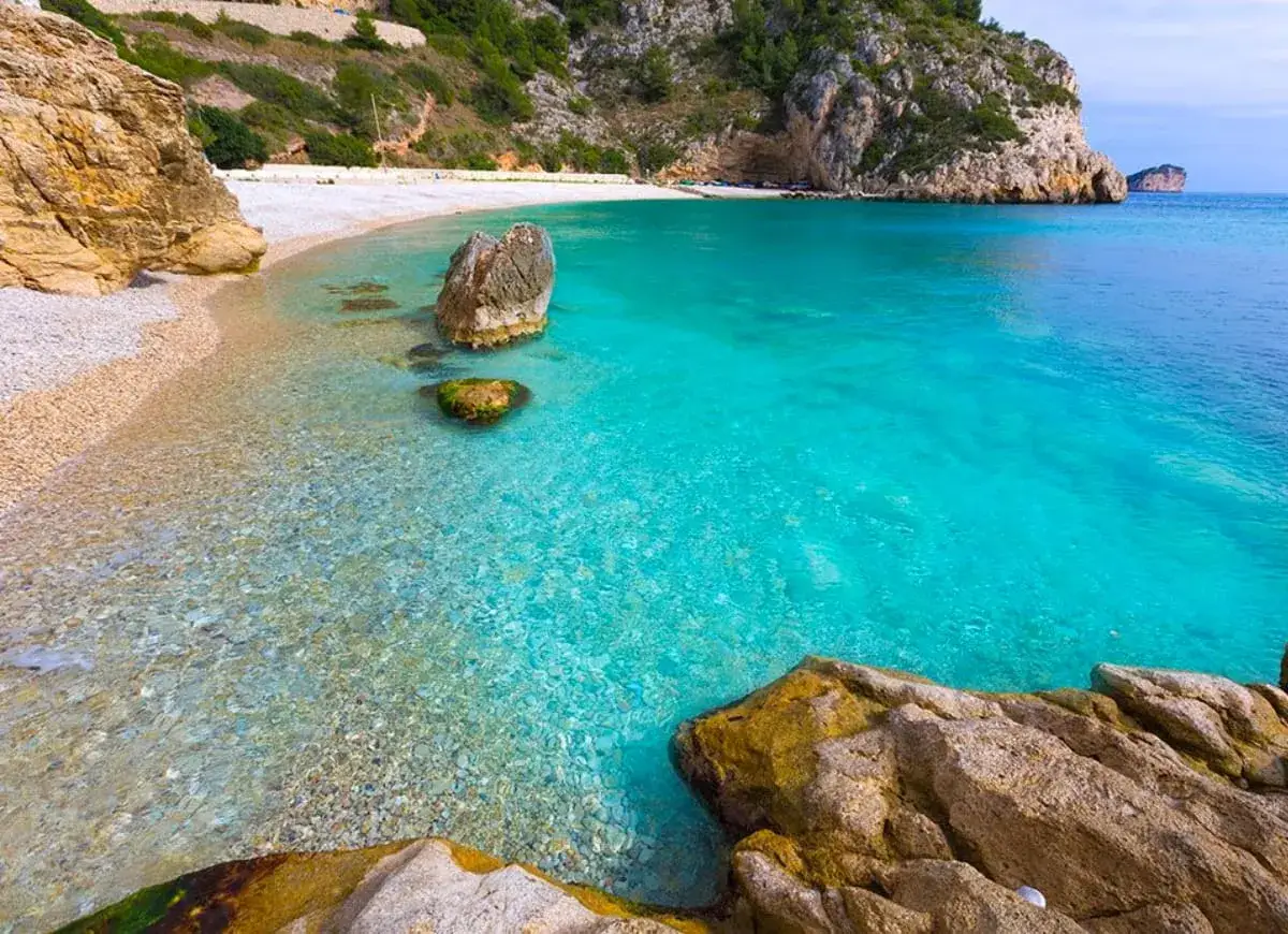 Aguas cristalinas y rocas doradas en una de las playas tranquilas de Alicante. Un paraíso escondido.