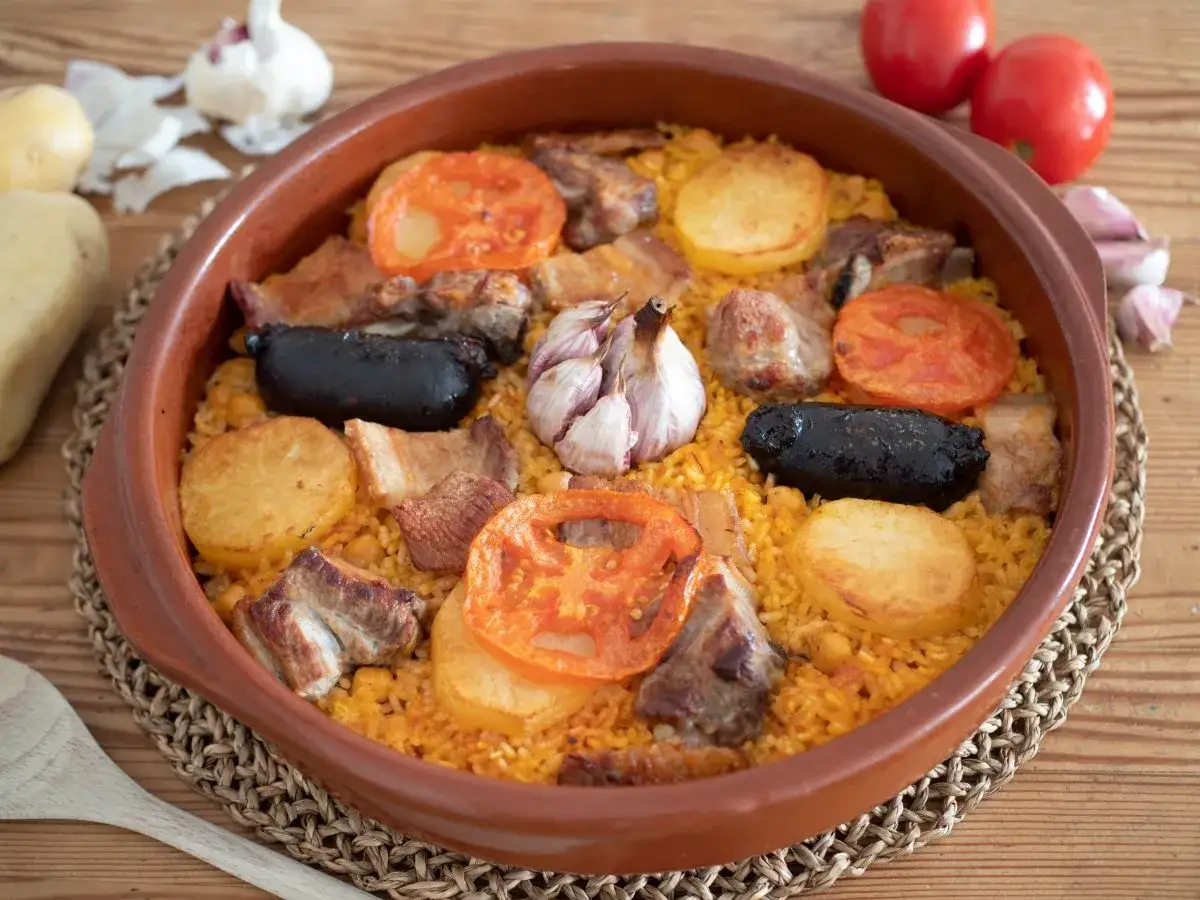 Arroz al horno en cazuela de barro, con trozos de carne, morcilla, patatas y tomates.