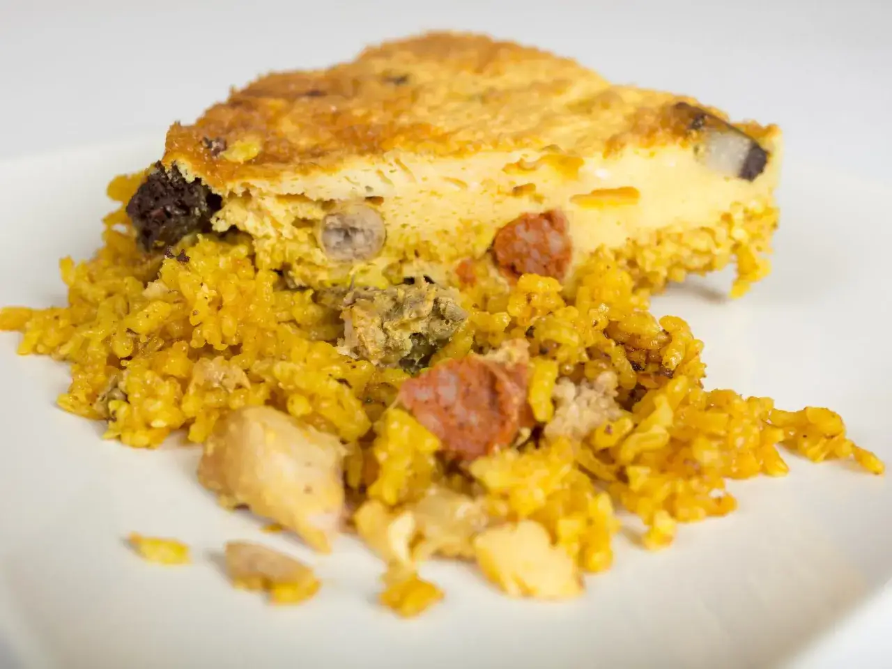 Un trozo de arroz con costra de Elche, con trozos de chorizo, pollo y huevo.