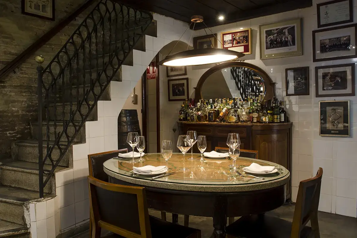 Elegante mesa puesta en un rinc&oacute;n acogedor de una casa monta&ntilde;a en Valencia, con una escalera de piedra y bar a la vista.