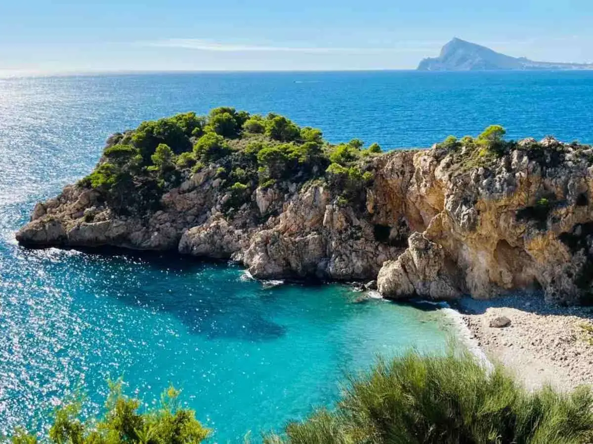 Una cala escondida con aguas turquesas y rocas escarpadas, un rincón idílico entre las mejores calas de Altea.