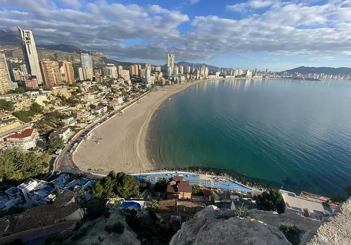 Vista panorámica de la mejor playa de Benidorm, Levante o Poniente, con su extensa arena dorada, el mar turquesa y la silueta de los rascacielos.