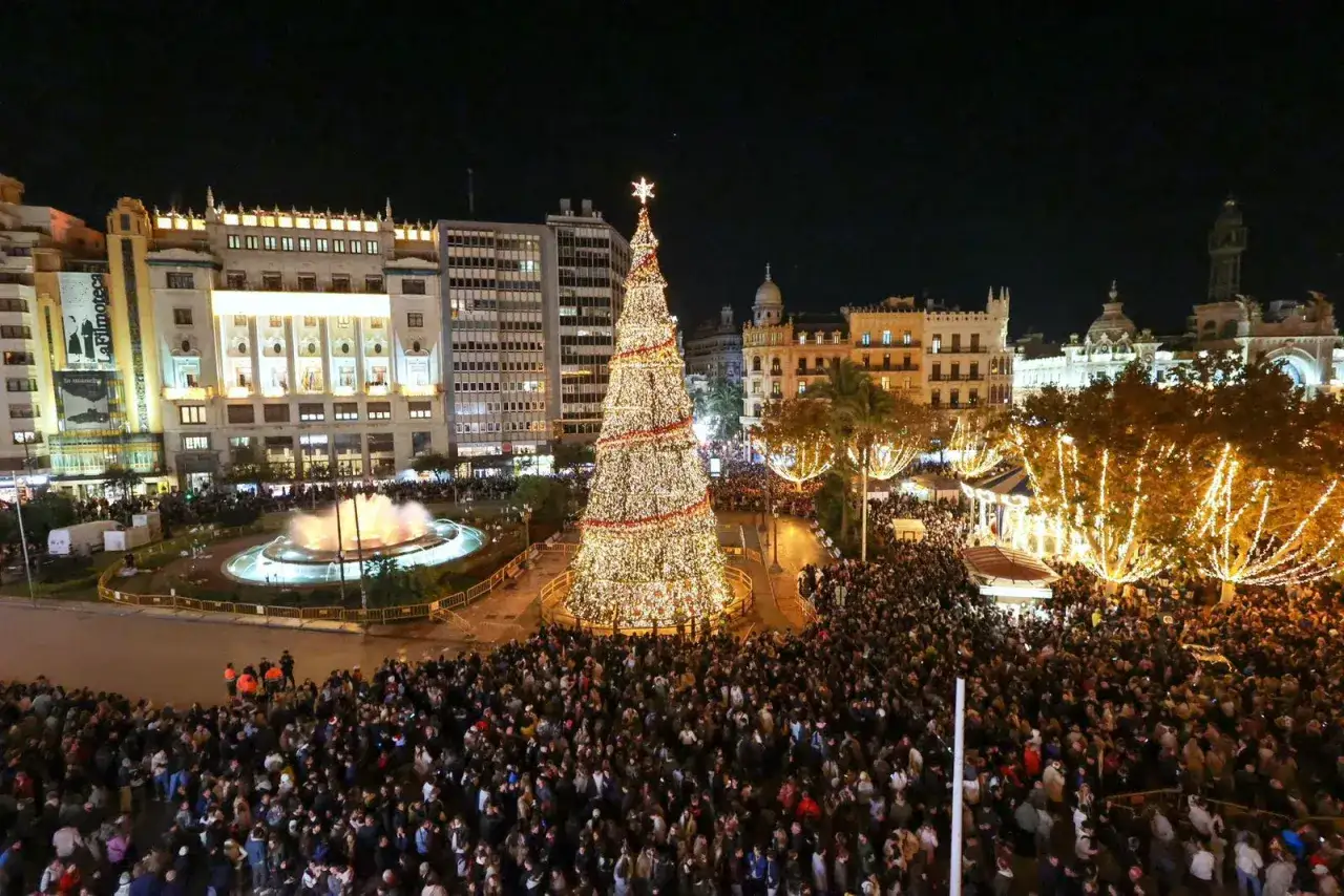 Gran árbol de Navidad iluminado en el centro de Valencia, rodeado de gente y edificios con encendido luces valencia.