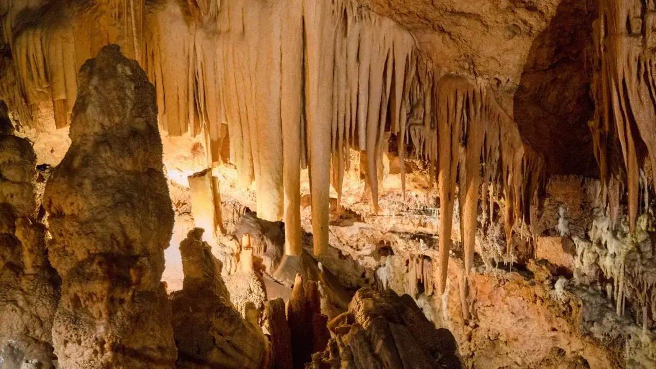Impresionantes estalactitas y estalagmitas iluminadas en la cueva del Rull, creando un paisaje subterr&aacute;neo m&aacute;gico.