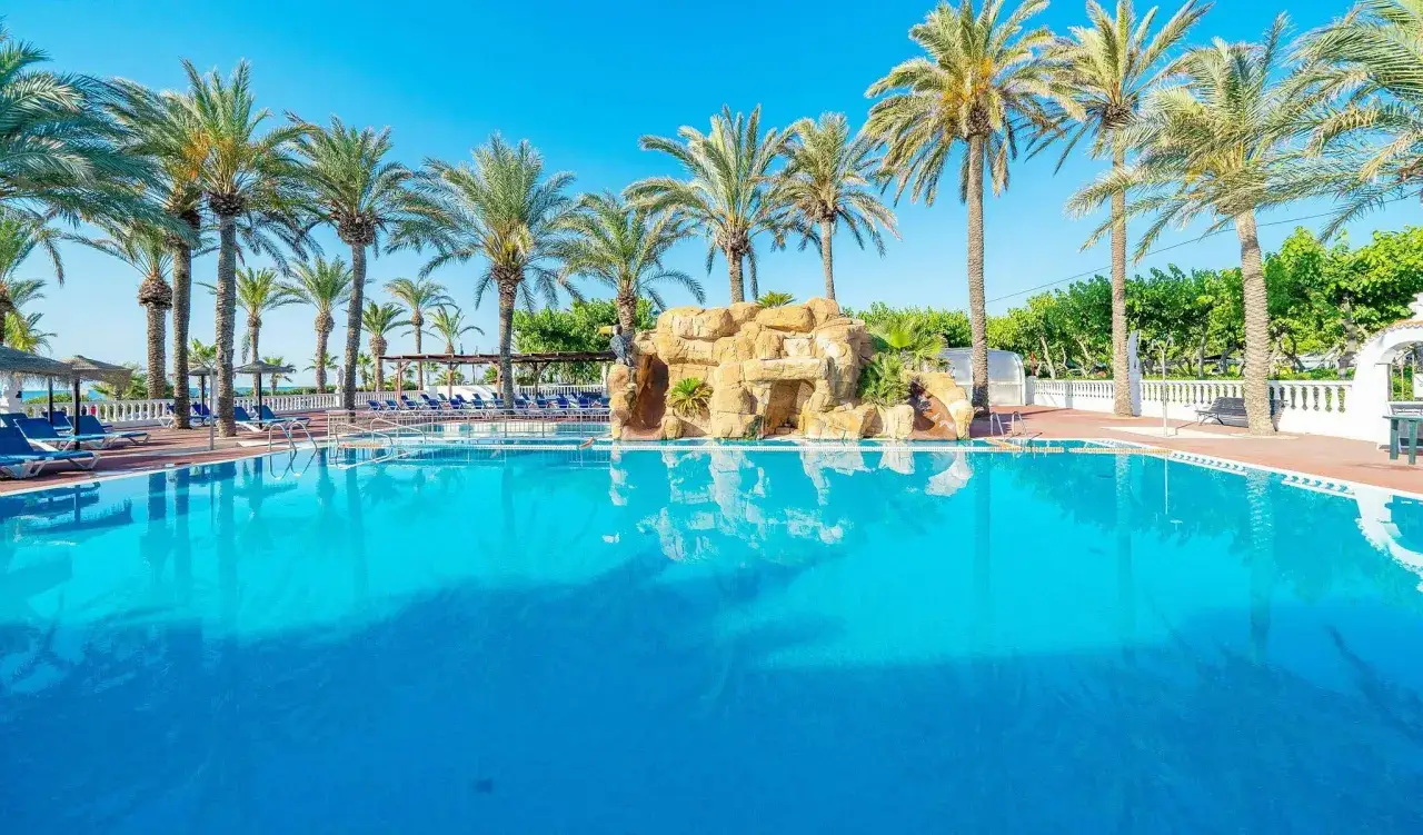 ¡Bravo, playa! Una piscina azul cristalina rodeada de palmeras y una cascada artificial. ¡El paraíso vacacional!
