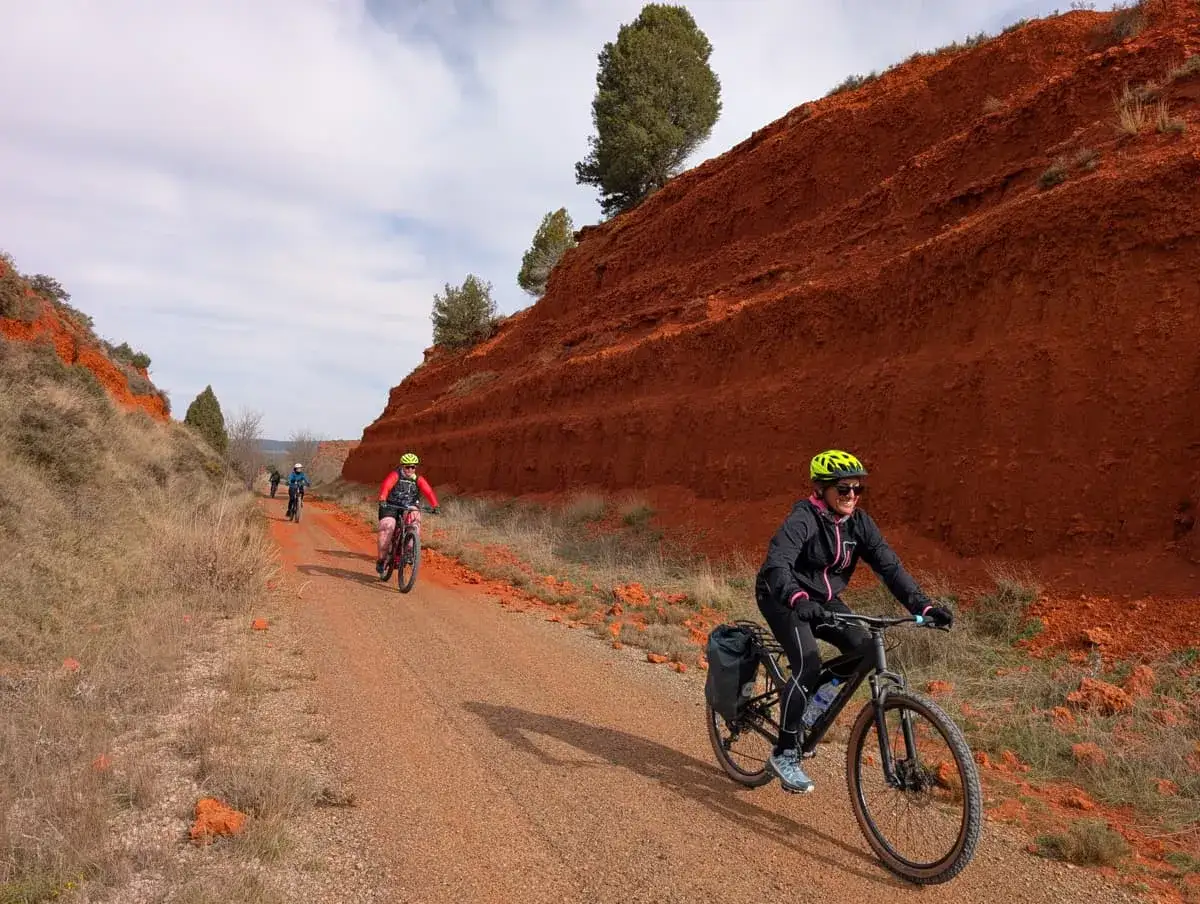 Ciclistas disfrutan de la v&iacute;a verde en Valencia, rodeados de impresionantes formaciones rojas.