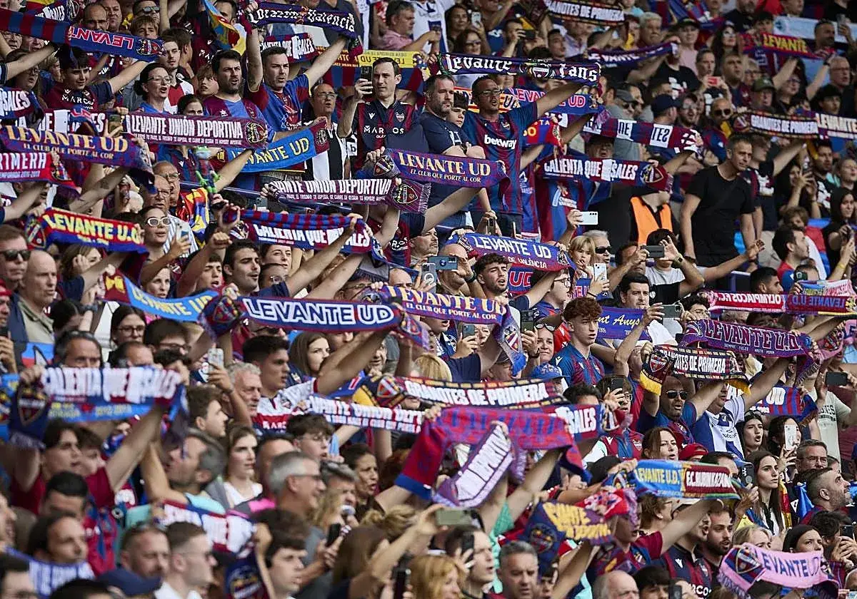 Aficionados del Levante UD celebran en el estadio Ciutat de València, ondeando bufandas con el lema