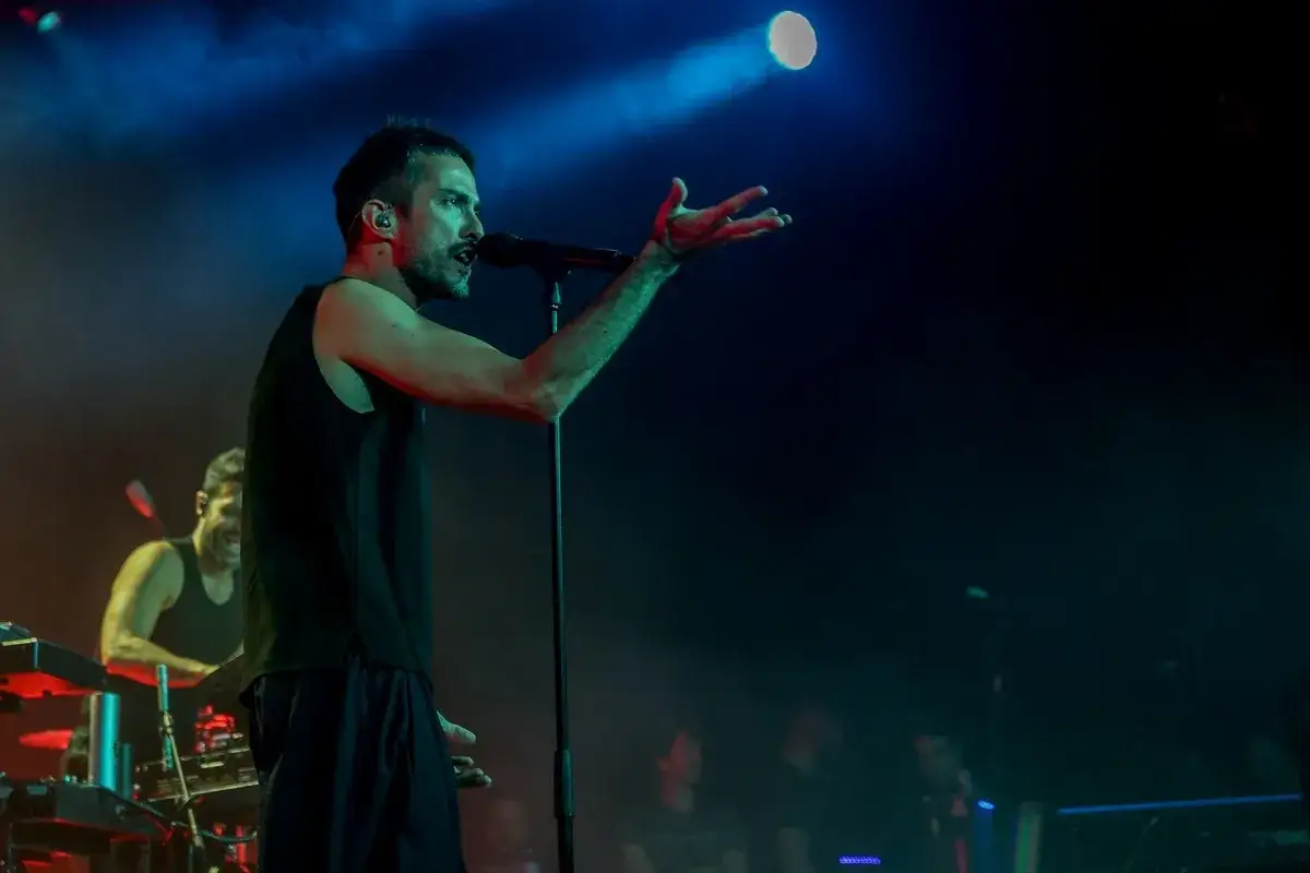 El cantante de Vetusta Morla en Valencia, con un micrófono y rodeado de luces de concierto.