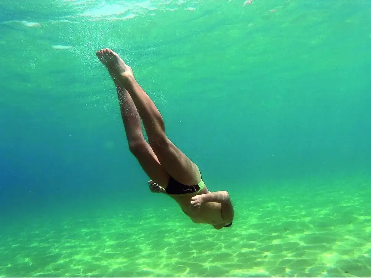 Buceo en la cala del llop mari, con el sol filtrándose en el agua turquesa y el fondo arenoso.